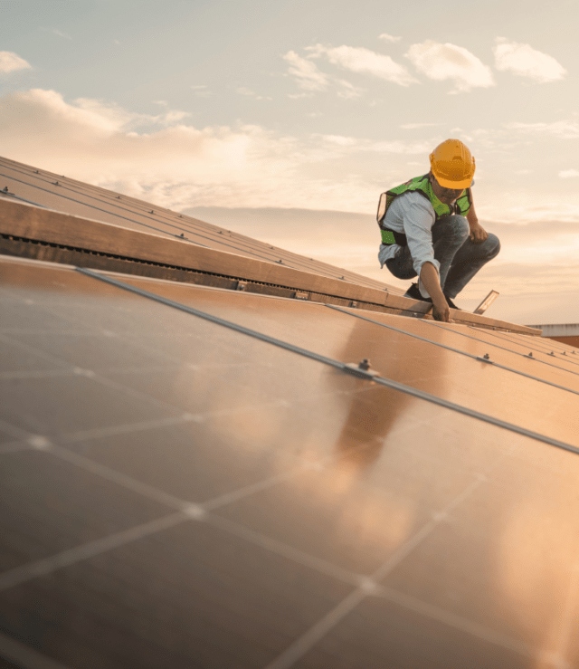 work man on a roof with solar panels