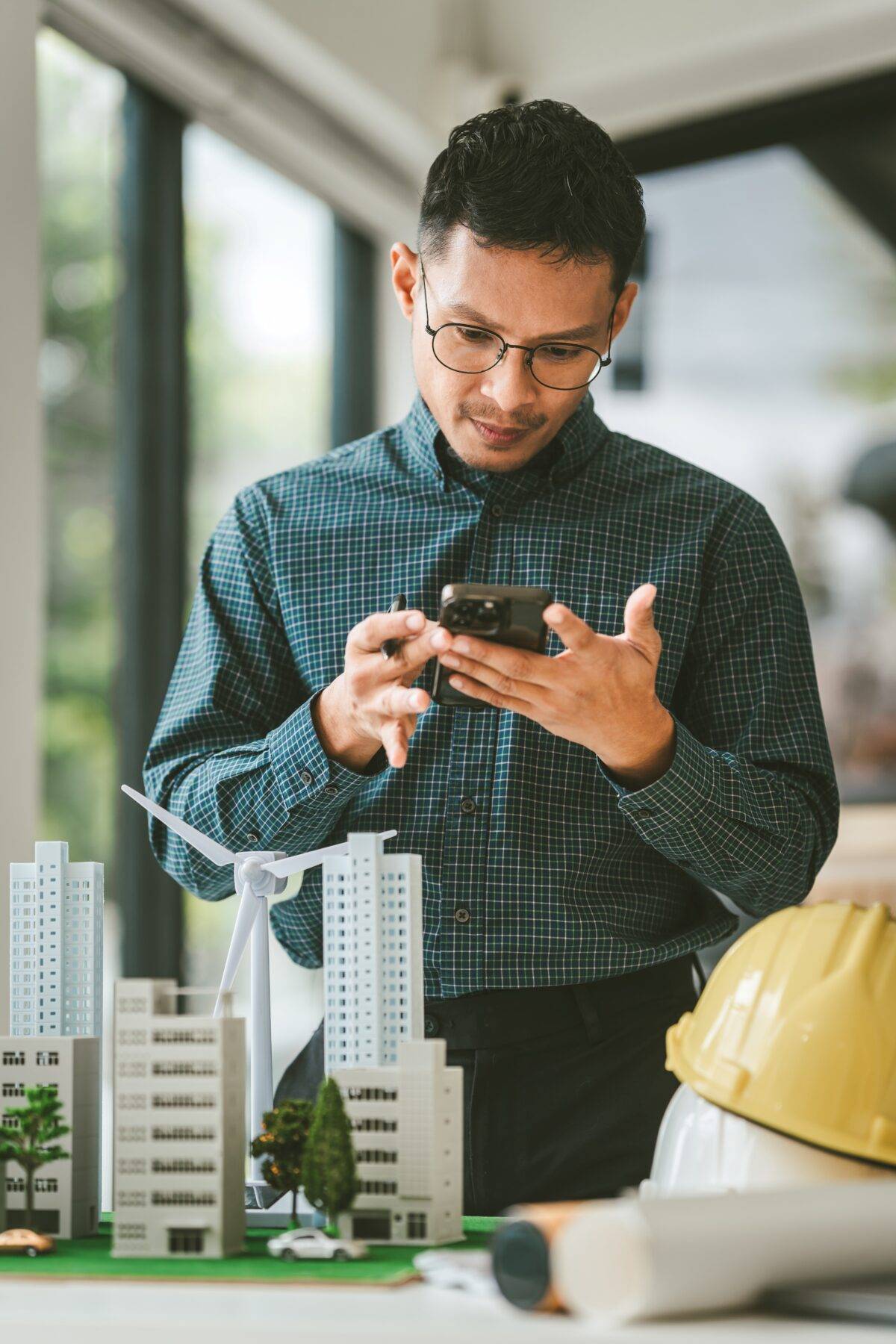 Man looking at phone over model of wind turbine